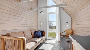 A cozy room with a wooden ceiling, a sofa, a dining table, and a chair. - 2 bedroom nice home in Hadsund (Hadsund)