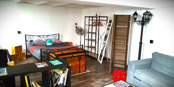 A bedroom with a bunk bed, a desk with books, a red dice, and a staircase.