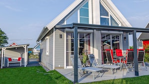Una casa moderna con un patio cubierto y mobiliario exterior.