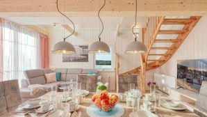 Un comedor con una mesa de madera dispuesta para seis personas, un sofá y una escalera.