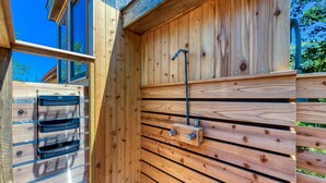 Una baita in legno con una panca integrata, un rubinetto in metallo e una finestra.