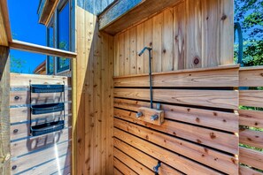 A wooden cabin with a built-in bench, a metal faucet, and a window.