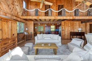 L’intérieur d’une cabane en bois, avec un plafond haut, un coin repas et une cuisine.