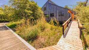 Un edificio moderno in legno con un patio in legno che vi conduce.