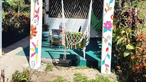 Una silla hamaca colgada bajo un arco colorido con la leyenda 'Lodge Natan' arriba.