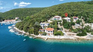 Un village côtier avec des maisons construites sur une colline, surplombant une marina où sont amarrés des bateaux.