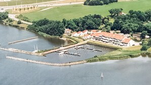Ett flygbildsfoto av ett hotell vid en sjö, med flera byggnader, en småbåtshamn med båtar och en omgivande park.