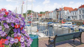 A marina with boats docked, a bench, and colorful flowers in the foreground.
