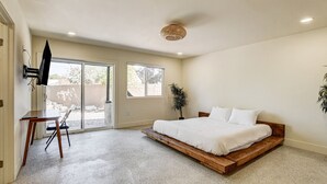 Un dormitorio con cama, escritorio y televisor.