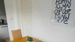 A dining table with four chairs, a potted plant, and a candle. - Clean & Cosy 3 Bed House with Free Pvt Parking (Croydon)