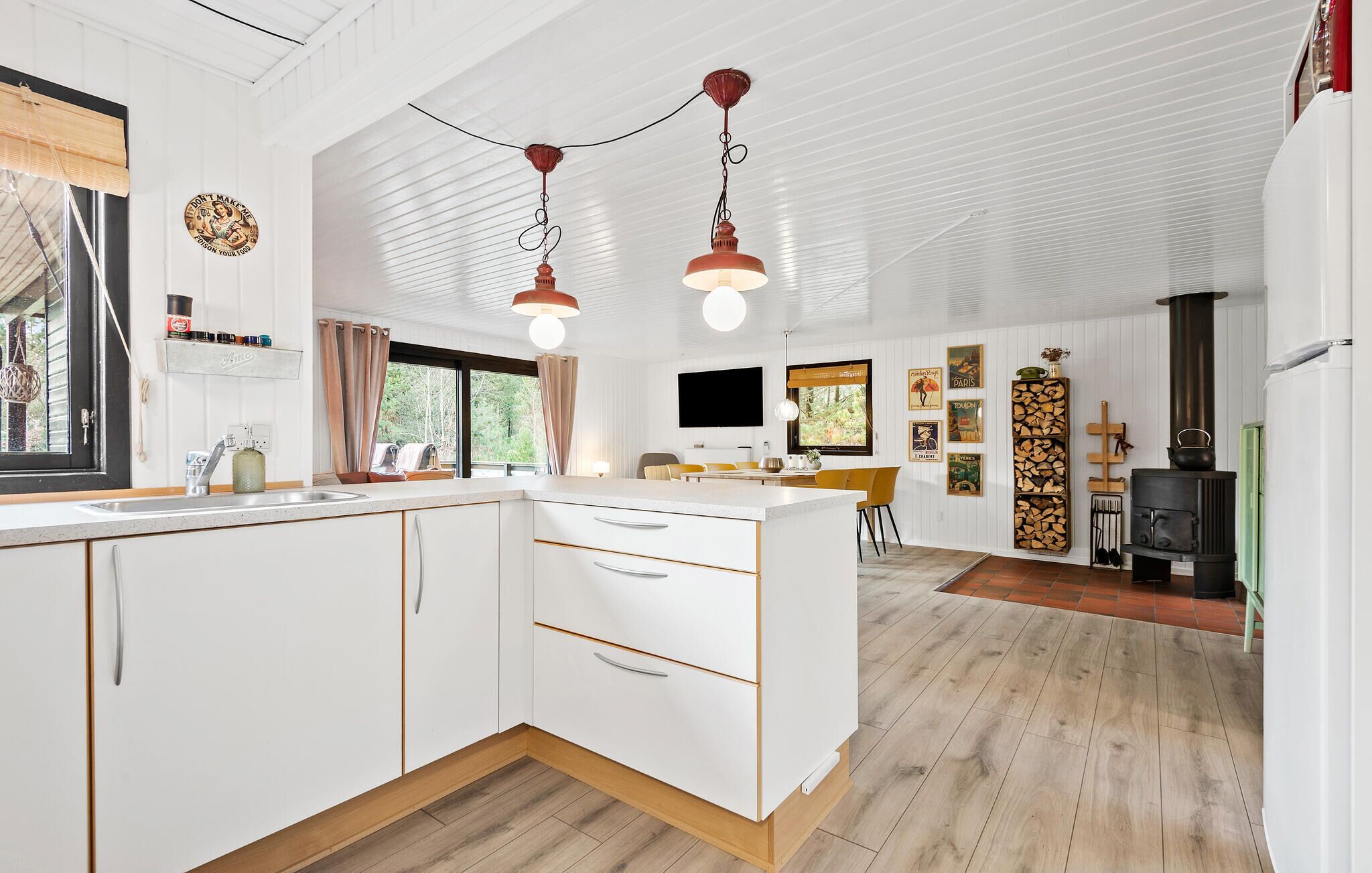 Et moderne køkken med hvide skabe, en central ø og hængende lamper.