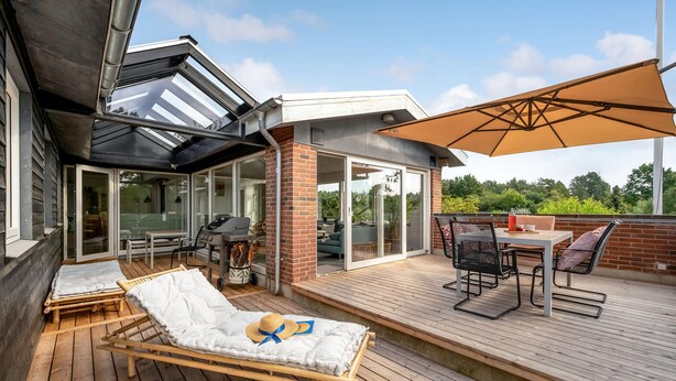 A deck with a lounge chair, a table with chairs, and a barbecue grill. - Stunning home in Ebeltoft with kitchen (Ebeltoft)