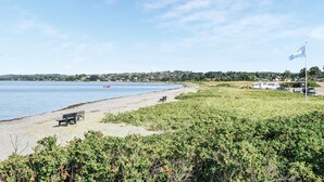 A beach with a bench, a flag, and a row of houses in the background. - Stunning home in Ebeltoft with kitchen (Ebeltoft)
