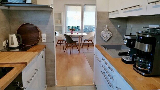 Una cocina moderna con microondas, tetera, cafetera y un comedor con mesa y sillas.