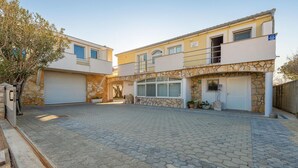 A two-story building with a stone facade, a covered entrance, and a paved courtyard. - StunNing apartment in Nin with WiFi (Nin)