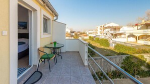 A balcony with a table and chairs, a small garden area, and a view of surrounding buildings. - StunNing apartment in Nin with WiFi (Nin)
