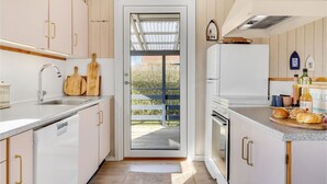 A modern kitchen with white cabinets, a stainless steel sink, and a wooden cutting board. - Lovely home in Juelsminde with kitchen (Juelsminde)