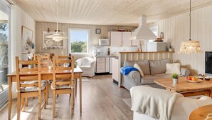 A spacious living area with a wooden dining table, chairs, a sofa, and a kitchen in the background. - Lovely home in Juelsminde with kitchen (Juelsminde)