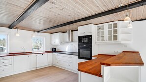 Een moderne keuken met witte kasten, een houten aanrechtblad en een zwarte oven.