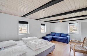 Relax in a serene bedroom with a large bed, sofa area, and wooden chair.