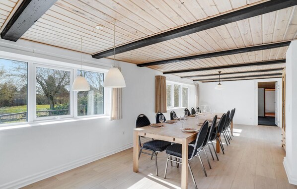 Ein geräumiger Essbereich mit einem langen Holztisch, schwarzen Stühlen und Pendelleuchten.