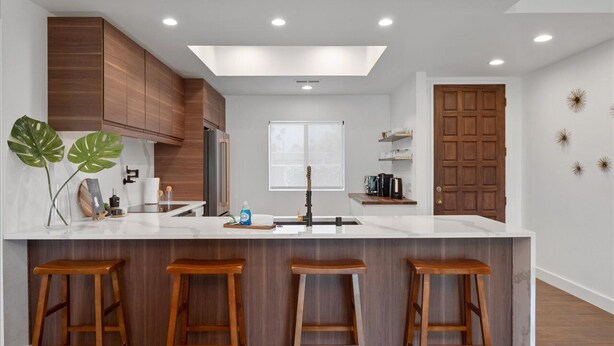 A modern kitchen with a central island, wooden stools, and a skylight. - LUXURY mid century modern Palm Springs/Golf cart & bicycles/best view (Cathedral City)
