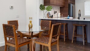 A modern kitchen with wooden cabinets, a glass dining table, and bar stools. - LUXURY mid century modern Palm Springs/Golf cart & bicycles/best view (Cathedral City)