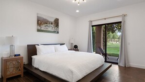 A modern bedroom with a large bed, a nightstand, a lamp, and a painting on the wall. - LUXURY mid century modern Palm Springs/Golf cart & bicycles/best view (Cathedral City)