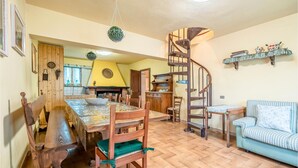 Ein gemütlicher Essbereich mit Holztisch und -stühlen, einer Wendeltreppe und einem kleinen Sofa.