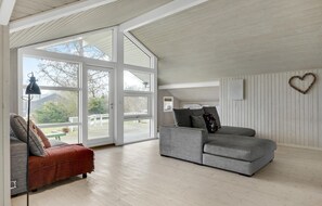 Relax in a spacious room with a high ceiling, large windows, and a comfortable seating area featuring a sofa and armchair.
