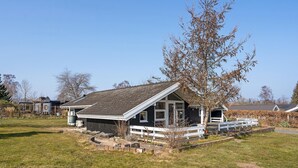 Une maison avec un toit en pente, une véranda dotée de balustrades blanches et un petit jardin.