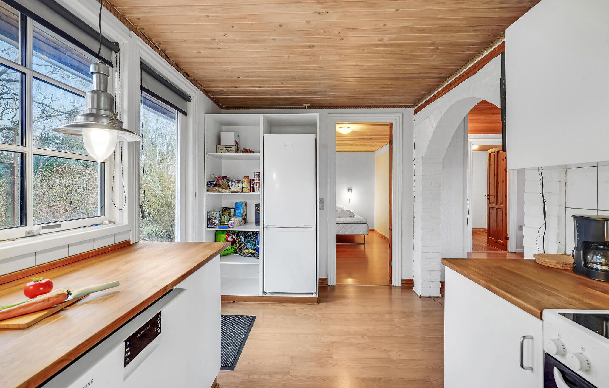 Une cuisine moderne avec des plans de travail en bois, un lave-vaisselle encastré et un réfrigérateur blanc.