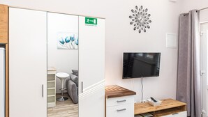 Een hotelkamer met een houten kast, een flatscreen televisie, een schilderij en een wandklok.