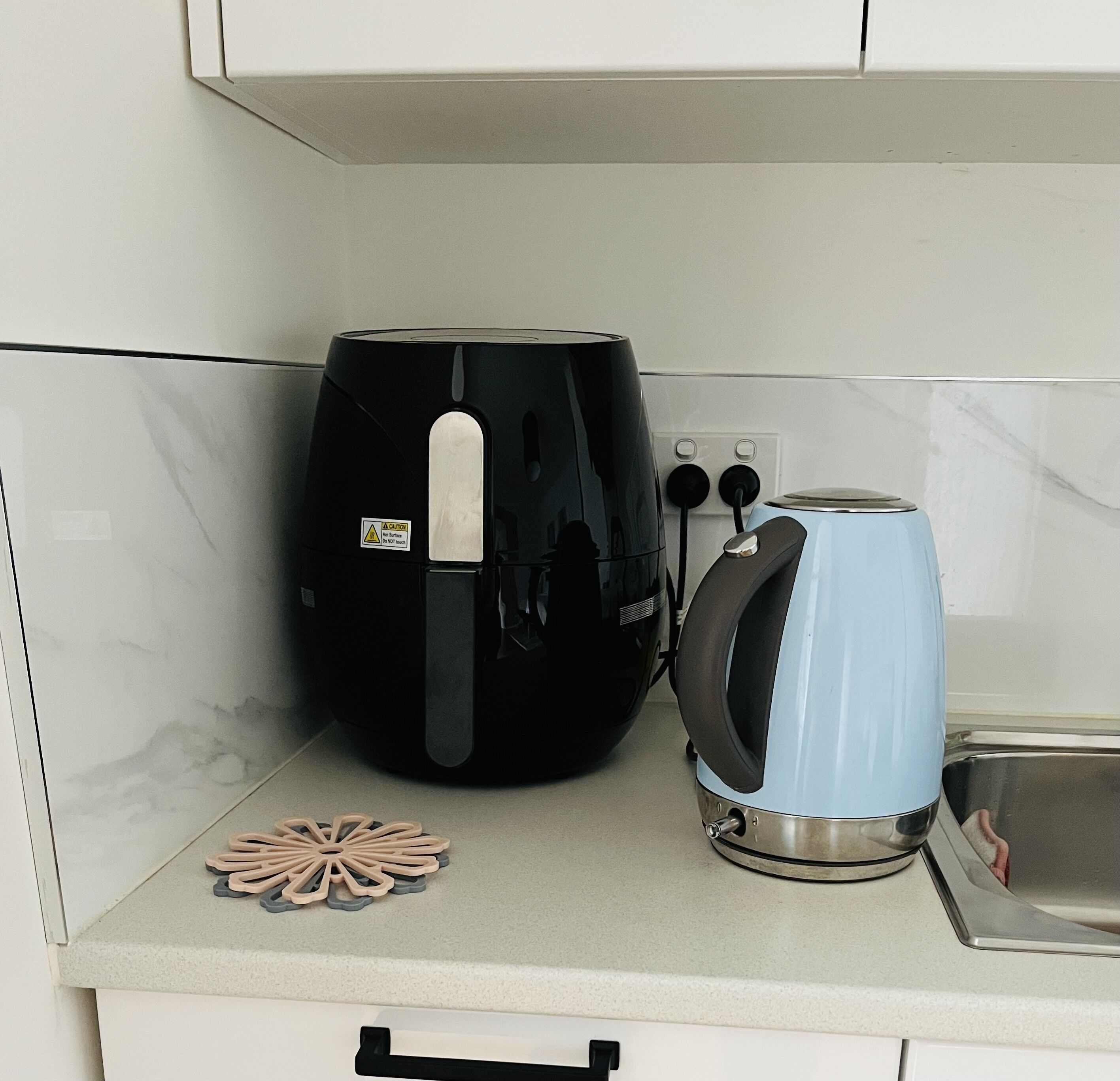 Een keukentafel met een zwarte koffiezetapparaat, een blauwe waterkoker en een decoratief object.