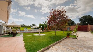 A well-maintained outdoor area with a lawn, a decorative fountain, and a covered seating area with umbrellas. - Amazing home in Guillena (Guillena)