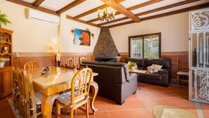 A spacious living area with a fireplace, a dining table with chairs, a sofa, and a decorative ceiling. - Amazing home in Guillena (Guillena)