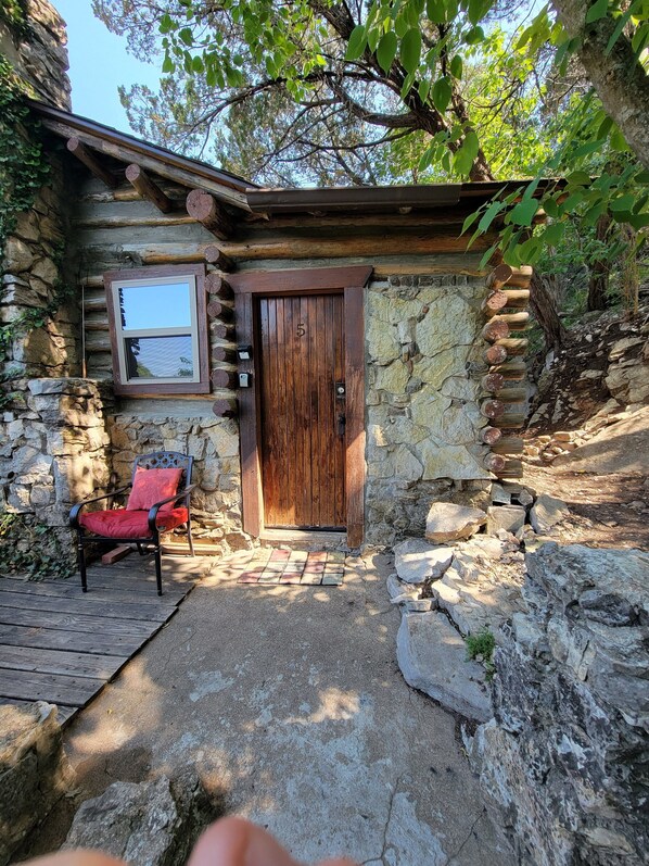 Cozy cabin with a stone exterior, wooden door, and a small porch area.