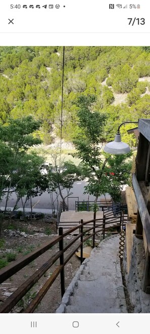 Enjoy a serene view from this balcony overlooking a lush landscape with trees and shrubs.