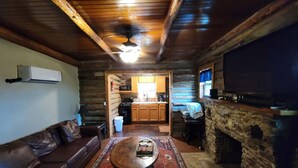 L’intérieur d’un chalet confortable en bois, avec un salon, une cuisine et une cheminée en pierre.