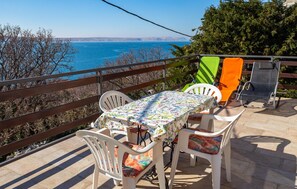 Une terrasse avec une table et des chaises, une vue sur la mer et une rambarde.