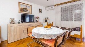 Un comedor acogedor con una mesa redonda, sillas, un armario de madera, un televisor y un jarrón decorativo.