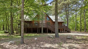A log cabin surrounded by tall trees in a forest. - Family Friendly Luxury Log Cabin (Broken Bow)