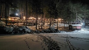En snedækket strand med fodaftryk, der fører hen til en bygning med et oplyst skilt.