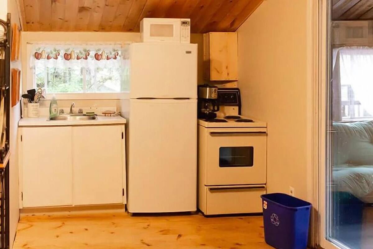 A compact kitchen with white cabinets, a white refrigerator, a stove, and a microwave.