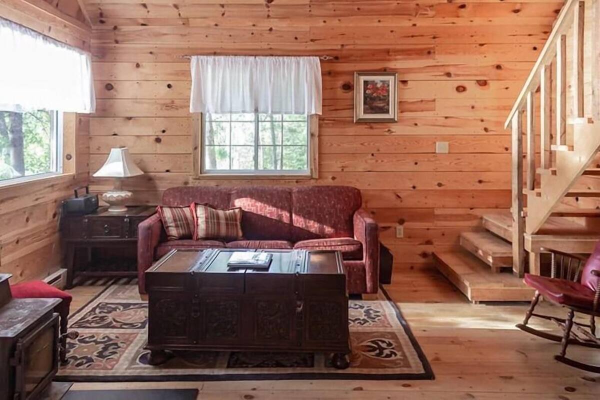 A log cabin interior with a sofa, coffee table, and a staircase.