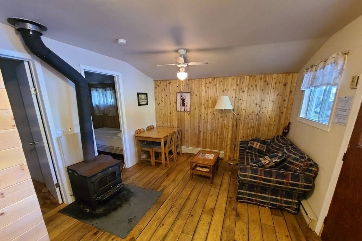 A cozy living room with a wood-burning stove, a sofa, a table, and a ceiling fan.
