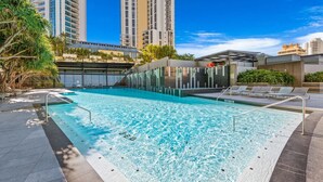 A rooftop swimming pool with clear blue water, surrounded by lounge chairs and a glass-enclosed area. - Circle on Cavill Ocean View  Surfers Paradise (Surfers Paradise)