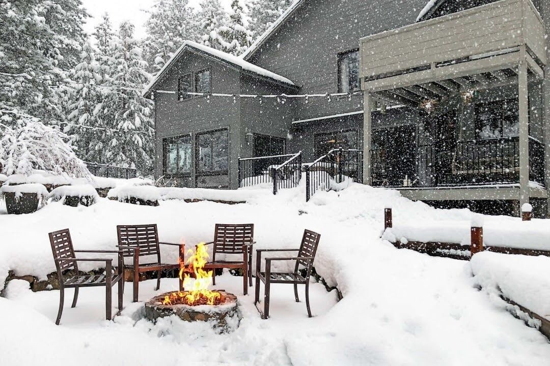 A snow-covered outdoor seating area with a fire pit and chairs.