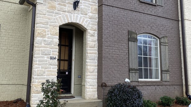 Une maison à deux étages avec une entrée en pierre, une boîte aux lettres et le numéro 804 sur la porte.