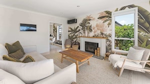 A modern living room with a fireplace, a sofa, a coffee table, and a chair. - Five Palms Luxury Beach Escape (Mount Maunganui)